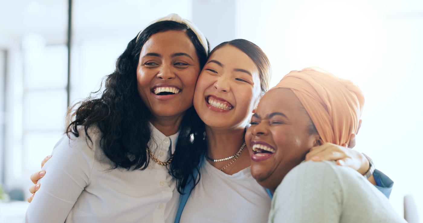 Three smiling women hugging.